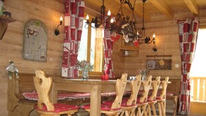 A wooden dining area with a long table and matching chairs, a wooden bench, and a wall-mounted menu. - Beautiful, spacious 12 person chalet, Portes du Soleil, France (Abondance)