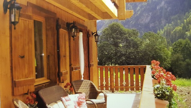 A wooden cabin with a balcony, wicker furniture, and a view of a mountainous landscape. - Beautiful, spacious 12 person chalet, Portes du Soleil, France (Abondance)