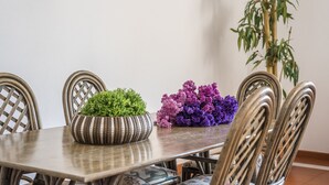 Una mesa de comedor con sillas, una planta en maceta y un jarrón con flores.