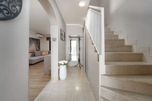 A hallway with a staircase, a sofa, and a vase of flowers. - Family-friendly,air-conditioned, quiet location, garden, barbecue, pets welcome. (Porec)