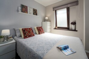 A bedroom with a bed, nightstand, lamp, wall art, and a window with a view. - Family-friendly,air-conditioned, quiet location, garden, barbecue, pets welcome. (Porec)