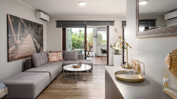 A modern living room with a grey sofa, a round coffee table, and a large painting of a bridge. - Family-friendly,air-conditioned, quiet location, garden, barbecue, pets welcome. (Porec)