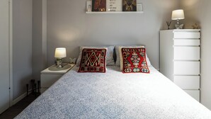 A bedroom with a bed, two pillows, a nightstand with a lamp, a dresser, and a wall art piece. - Family-friendly,air-conditioned, quiet location, garden, barbecue, pets welcome. (Porec)