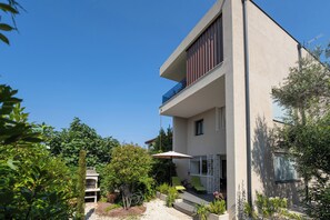 A modern two-story building with a balcony, outdoor seating area, and a garden. - Family-friendly,air-conditioned, quiet location, garden, barbecue, pets welcome. (Porec)