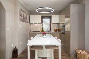 Een moderne keuken met een wit aanrechtblad, een hangende lamp en een vaas met bloemen.