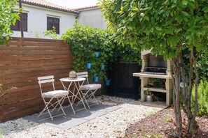 A patio with a wooden fence, a barbecue grill, and a seating area with chairs and a table. - Family-friendly,air-conditioned, quiet location, garden, barbecue, pets welcome. (Porec)
