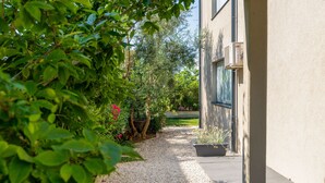 A pathway leading to a building with a gravel surface, surrounded by greenery and a potted plant. - Family-friendly,air-conditioned, quiet location, garden, barbecue, pets welcome. (Porec)