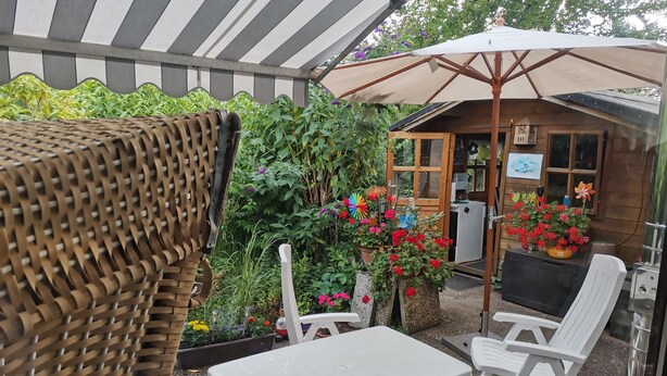 A covered outdoor seating area with wicker furniture, a table, and chairs. - Spacious u. child-friendly apartment (Oesterdeichstrich)