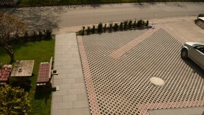 A paved outdoor area with a patterned walkway, a picnic table, and a car parked nearby.