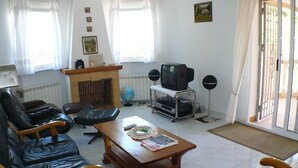 Una sala de estar con sillones de cuero, una mesa de centro de madera, un televisor y una chimenea.