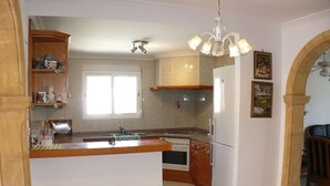 Una cocina con una isla central, armarios de madera, horno empotrado y refrigerador.