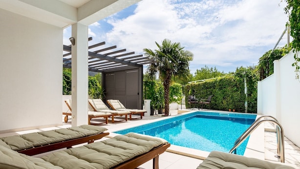 A modern outdoor pool area with lounge chairs and a pergola.