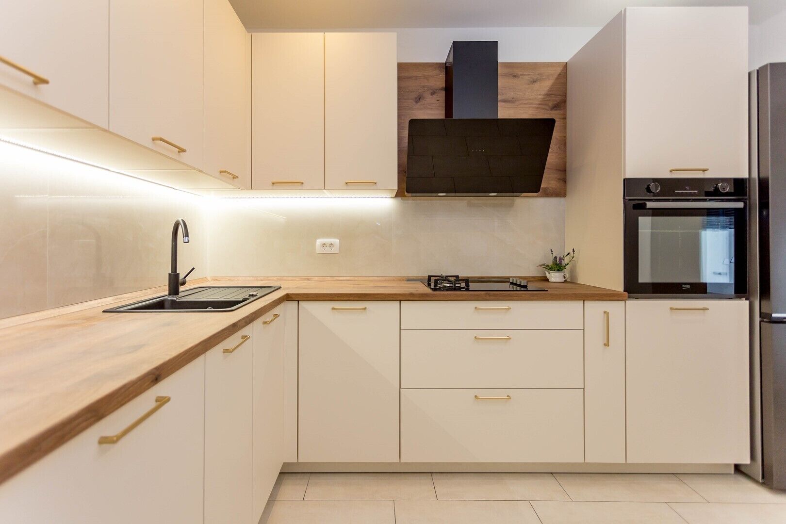 Eine moderne Küche mit weißen Schränken, einer Holz Arbeitsplatte, einem eingebauten Herd und einem Edelstahl-Kühlschrank.