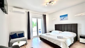 A modern hotel room with a large bed, a sofa, a small table, and a TV.