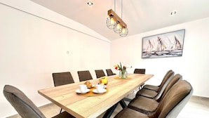 A modern dining room with a wooden table, six chairs, and a vase with flowers.
