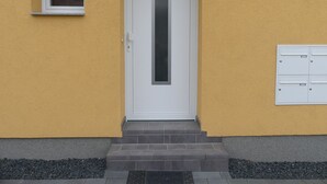 A building with a white door, a small window, and a mailbox.