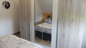 A bedroom with a bed, a bedside table, and a mirror.