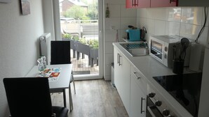 A compact kitchen with a dining area, a red cabinet, a microwave, and a view through the door.