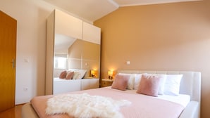 Une chambre avec un grand lit, un plaid blanc moelleux et un miroir au-dessus.
