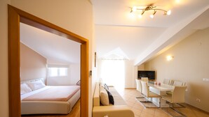 Un espace de vie moderne, ouvert et décloisonné, comprenant un lit, un canapé, une table à manger et un téléviseur.