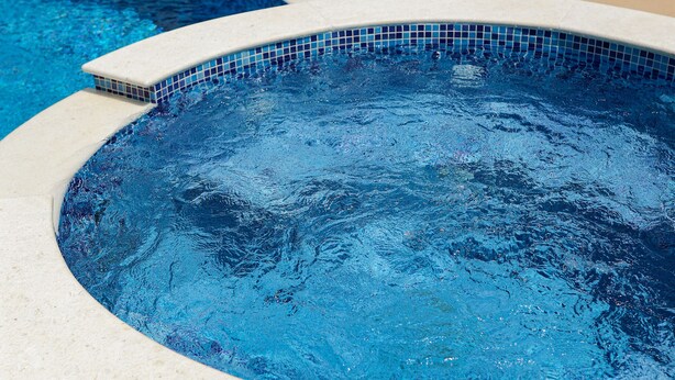 Une piscine avec des chaises longues et un bord carrelé.