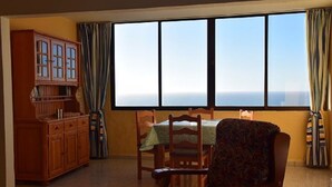 Un comedor con una mesa, sillas, un aparador de madera y un ventanal con vistas.
