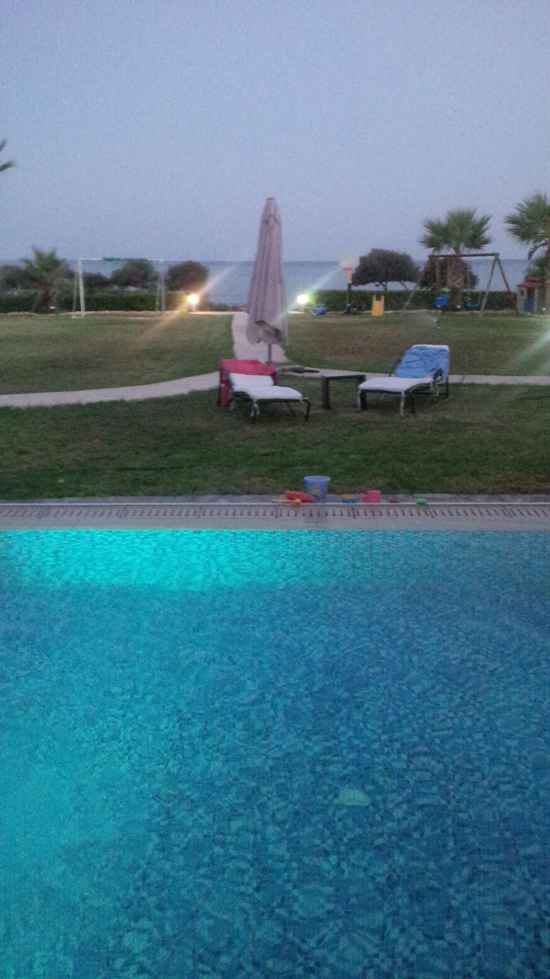 Une piscine avec des chaises longues et un parasol.