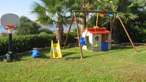 Een kinderspeelplaats met een schommel, een huisje en een basketbalveld.