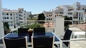 A balcony with a table and chairs, overlooking a cityscape with white buildings and a clear sky. - OFFERS FOR LAST DAYS!!, LUXURY ATTIC CARIHUELA,  2 GARAGES, POOL, INT. CHANNELS (Torremolinos)