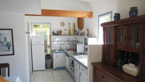 Una cocina con armarios blancos, un fregadero, una estufa y un cubo de basura.