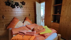 A wooden-paneled room with a bed, pillows, and a wardrobe.