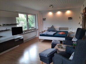 A modern bedroom with a bed, bedside table, lamp, and a TV on a stand. - Bright apartment Heidi 1st floor with fantastic valley view: KOLVENBACHER ZIEGENHOF (Kolvenbach)