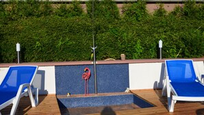 A poolside area with two blue lounge chairs, a red flamingo statue, and a metal pole.