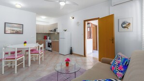 A compact living space with a dining area, kitchenette, and a sofa with a colorful pillow. - 400m from Materada beach, pool, sun loungers, air conditioning  (Porec)