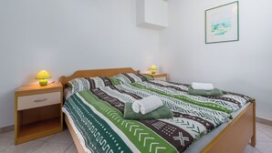 A neatly made bed with patterned bedding, two bedside lamps, a small bedside table with a drawer, and a framed picture on the wall. - 400m from Materada beach, pool, sun loungers, air conditioning  (Porec)