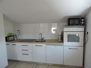 Kitchen equipped with a stainless steel sink, microwave, compact oven, and coffee maker.