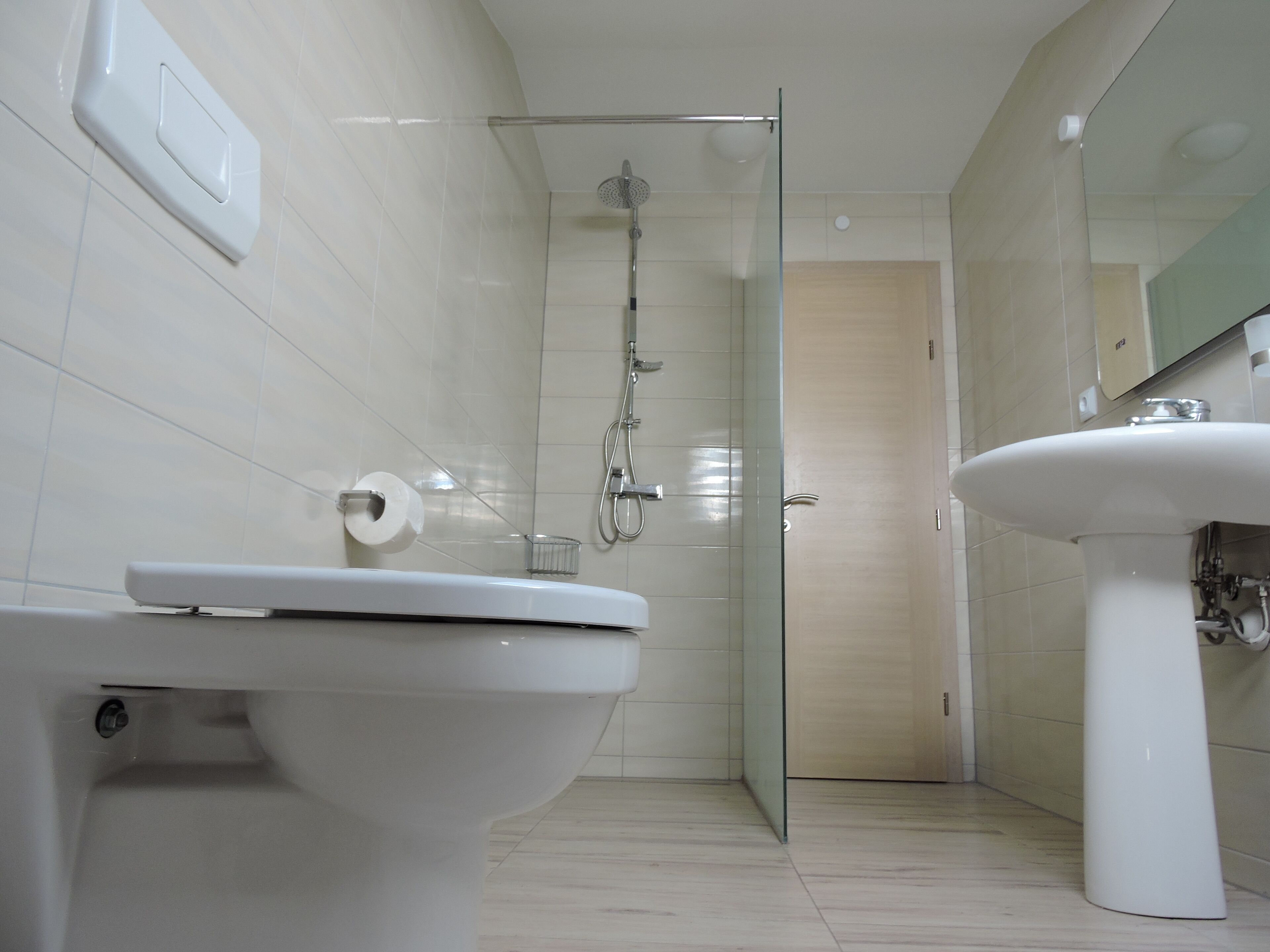 A modern bathroom with a toilet, shower, and sink.
