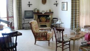 Un salon avec une cheminée, un téléviseur et un coin repas comprenant des chaises et une table.