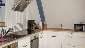 A modern kitchen with white cabinets, stainless steel appliances, and a wooden floor. - Holidays by the sea in a historic thatched house: WiFi, 2 Smart TVs, sauna from 2022 (Pommerby)