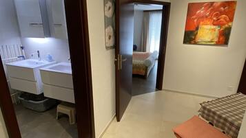 Ein Hotelzimmer mit Bad, einem Bett, einem kleinen Tisch und einem Gemälde an der Wand.