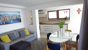 A modern living room with a grey sofa, a round glass table, and blue chairs. - Modern apartment near the beach for 4 people (Trogir)