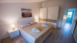 A bedroom with a bed, nightstands, a lamp, a cityscape painting, and a wardrobe. - Luxury villa Vitam in Imotski, private pool (Zmijavci)