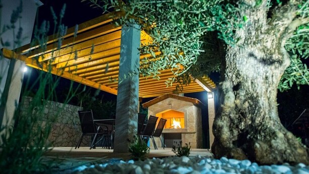 An outdoor patio area with a stone wall, a wooden pergola, and a stone fireplace. - Luxury villa Vitam in Imotski, private pool (Zmijavci)