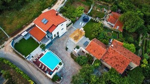 An aerial view of a residential area with a swimming pool, a red-roofed house, and a gazebo. - Luxury villa Vitam in Imotski, private pool (Zmijavci)