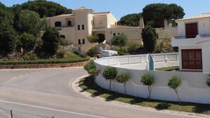 Zona residencial amb un carrer corbat, una tanca blanca i un senyal de parada.