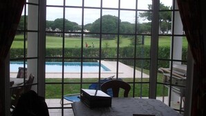 Habitació amb una finestra gran amb vista a una piscina i un jardí ben cuidat.