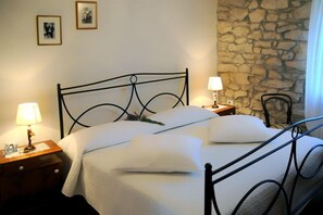 A neatly made bed with a metal frame, two bedside tables with lamps, and a stone wall.