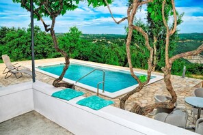 A pool area with a view of the countryside, including trees and a distant landscape.