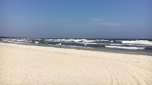 A wide sandy beach with gentle waves and a clear blue sky.