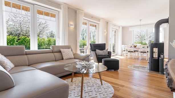 A modern living room with a beige sofa, a glass coffee table, and a patterned rug.